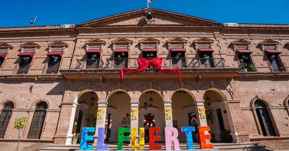 Los Mochis Travel Guide: Valle del Fuerte Charm Colorful El Fuerte sign in front of historic municipal building under clear blue sky.