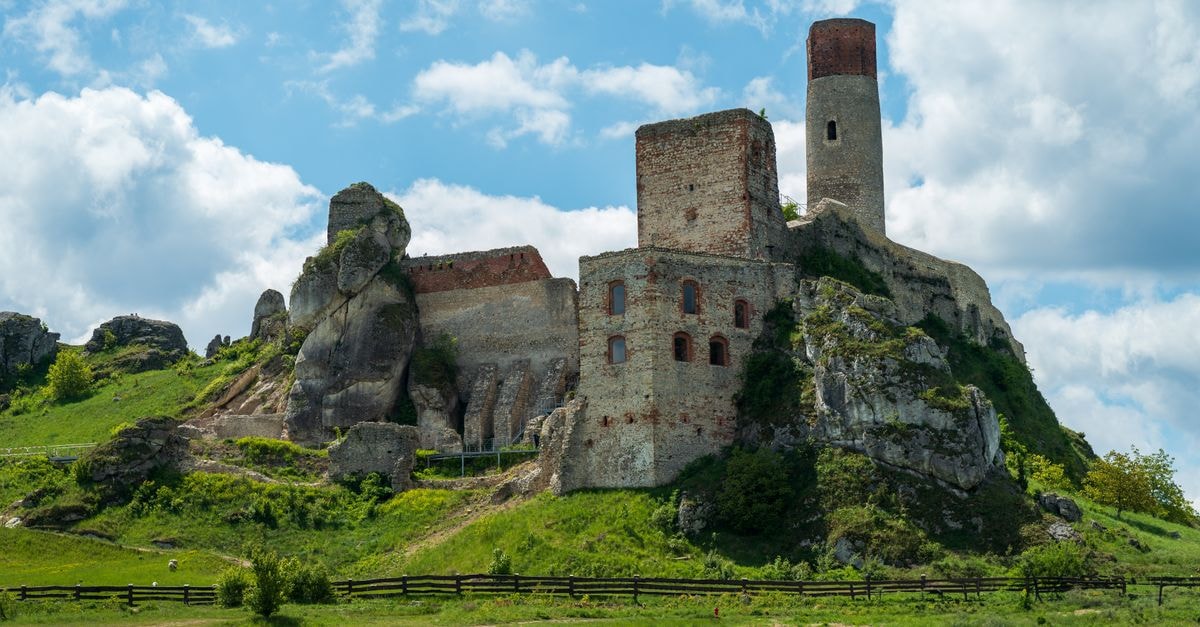 Explore the stunning ruins of Ogrodzieniec Castle amid scenic hills and blue skies in Olkusz, Poland.