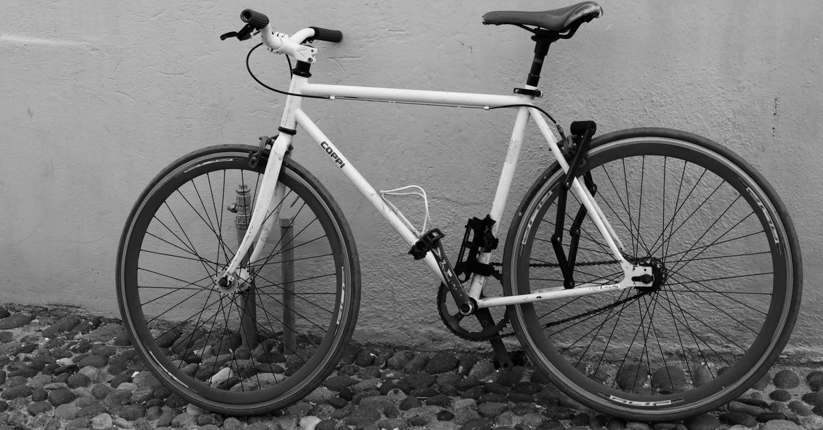A sleek bicycle leans against a textured wall in Alghero, Sardinia.