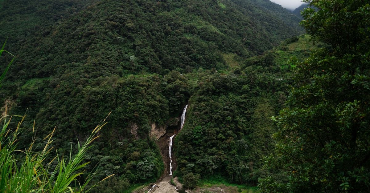 Puyo travel guide: gateway to Ecuador's Amazon lowlands Lush green mountains and a stunning waterfall in Banos, Ecuador create a tranquil nature scene.