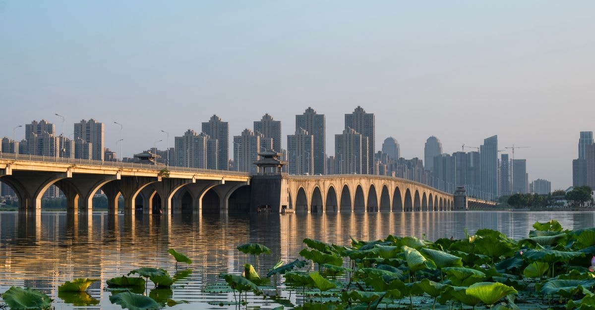 Tian Yuan Hotel in Mengzi: A Central Stay on Tianma Road Beautiful sunset view of Moshui Lake bridge with Wuhan cityscape in the background.