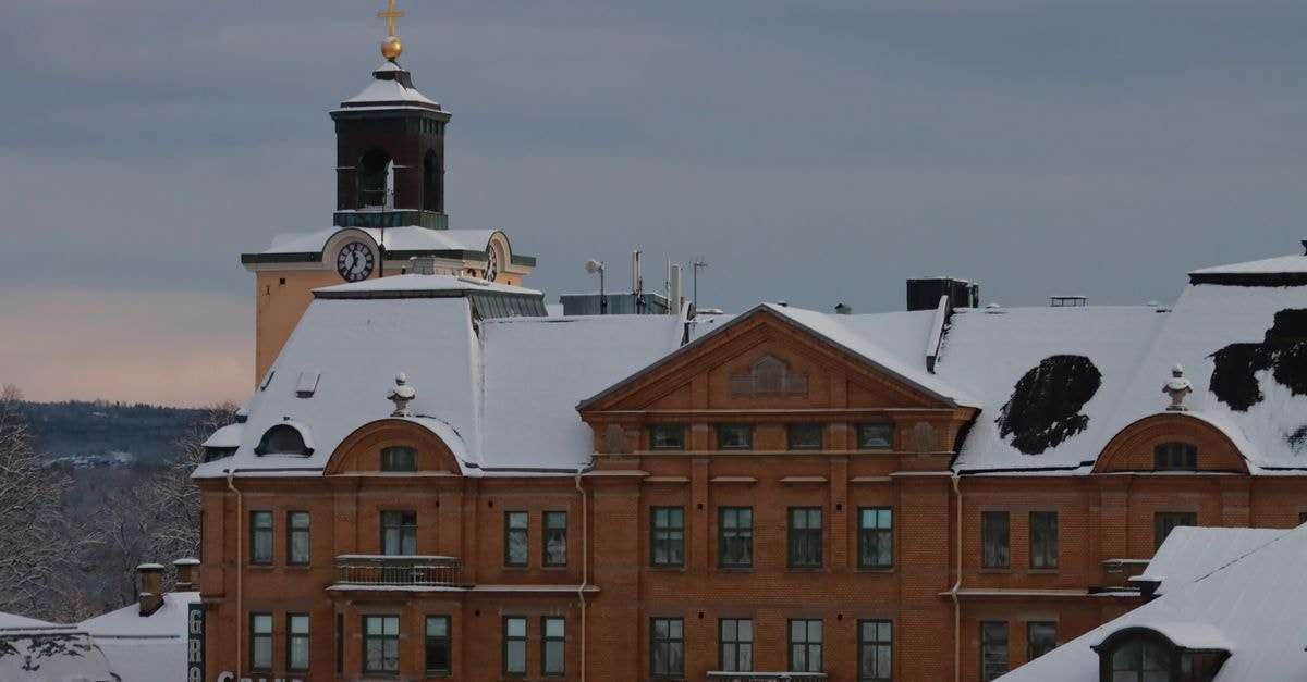 A stunning view of the snow-covered Grand Hotel building with a clock tower in winter.