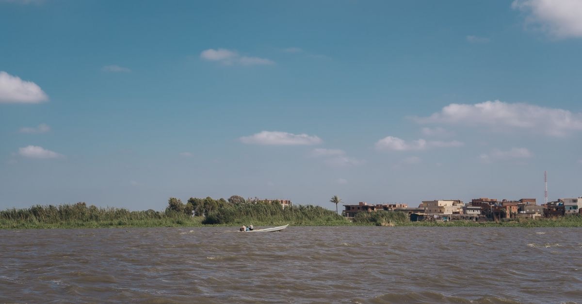 Malakal Travel Guide: Slow Days on the Upper Nile Tranquil view of a boat on the Nile River with village in the background.