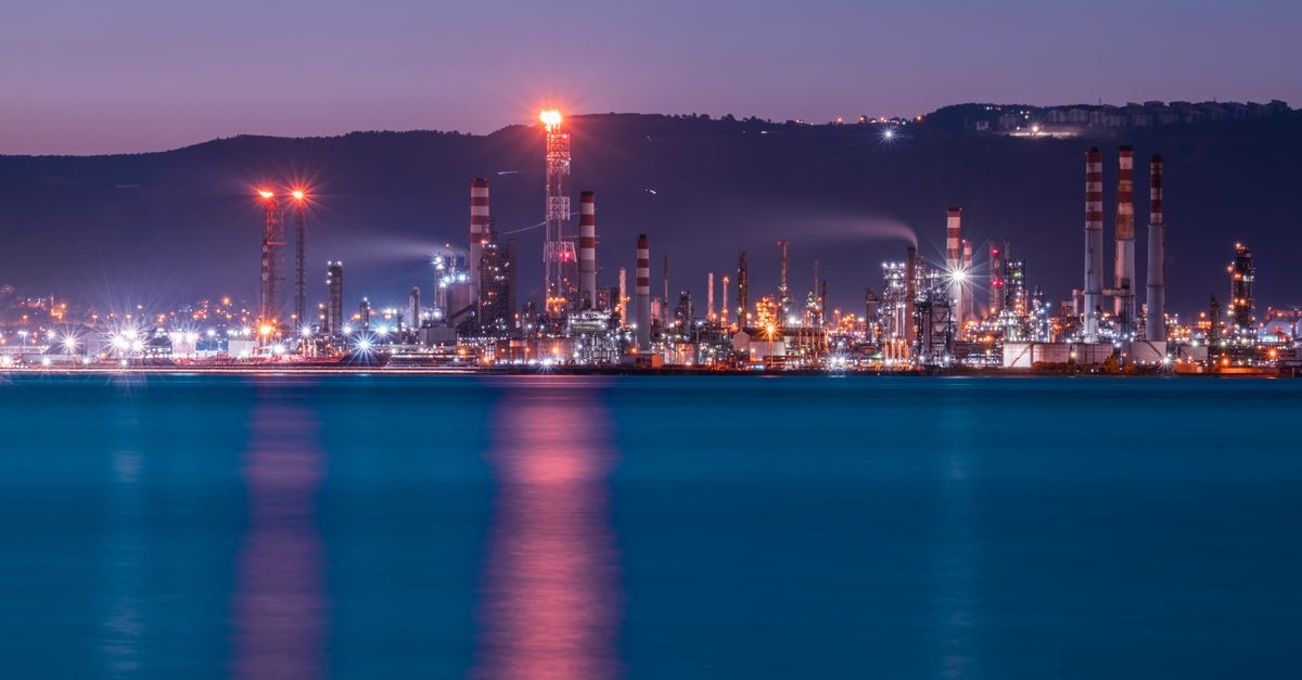 Vibrant twilight view of İzmit's industrial skyline with illuminated factories reflecting on the water.