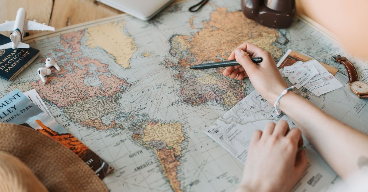 San Antonio Travel Guide: Planning Tips and Things to Do Hands marking destinations on a world map surrounded by travel essentials like passport and camera.