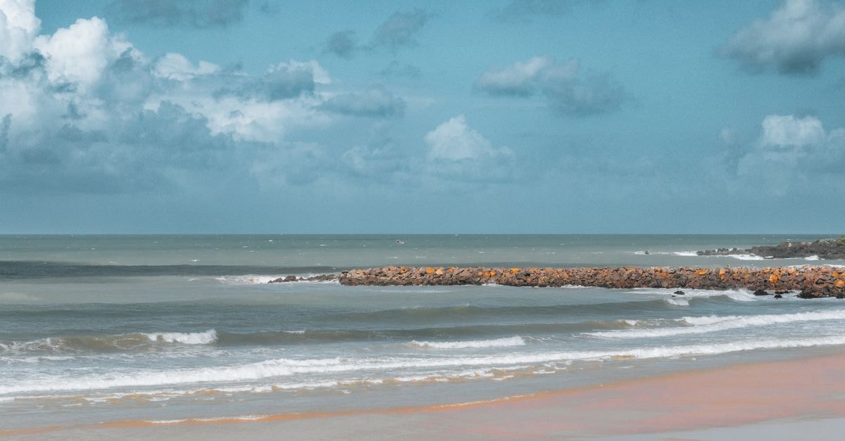 A tranquil beach scene with ocean waves and clouds in Natal, Brazil.