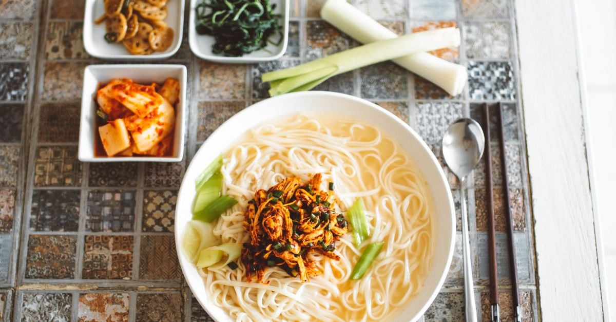 Chuncheon Travel Guide: Lakes, Buckwheat Noodles and Easy Day Trips Authentic Korean noodle soup served with kimchi and side dishes on a patterned table.
