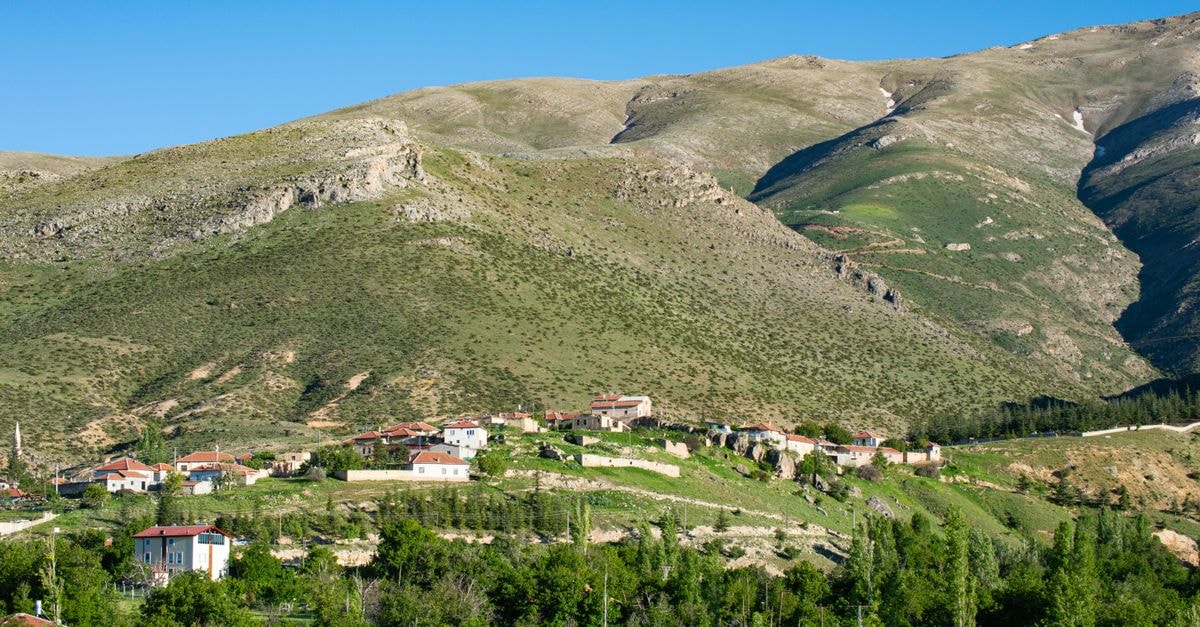 Khost Travel Guide: Mountains, Moments, and Local Flavor Scenic view of a charming village nestled in the lush mountains of Turkey under clear blue skies.
