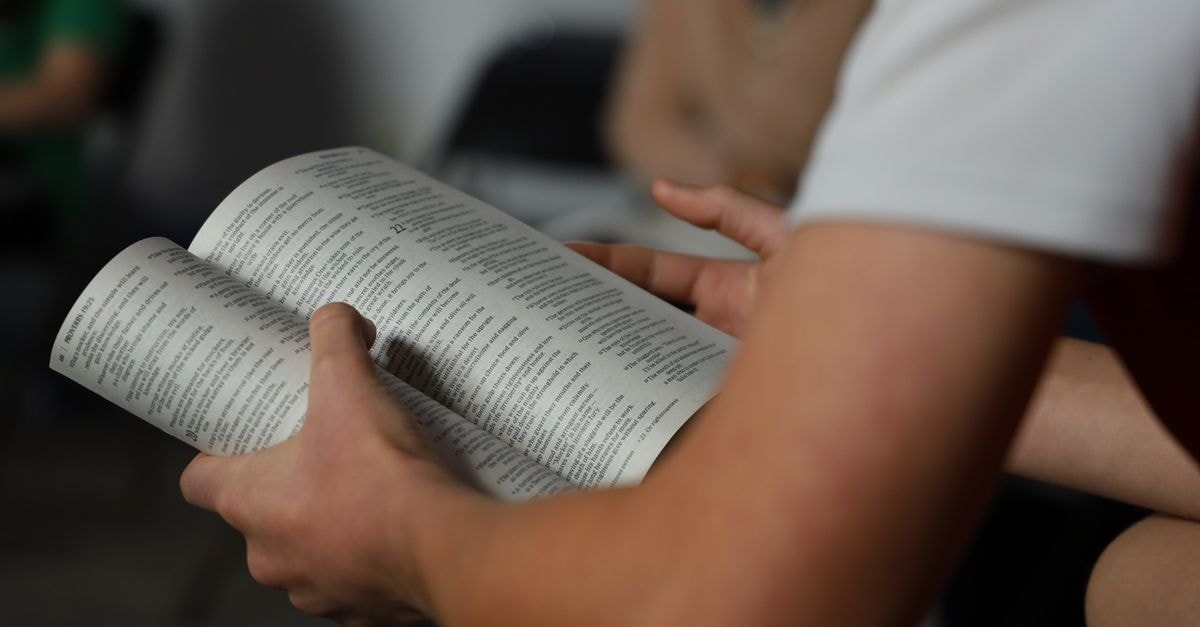 Kamina Travel Guide: Culture, Food and Practical Context Focused shot of hands holding an open book indoors, promoting reading and education.