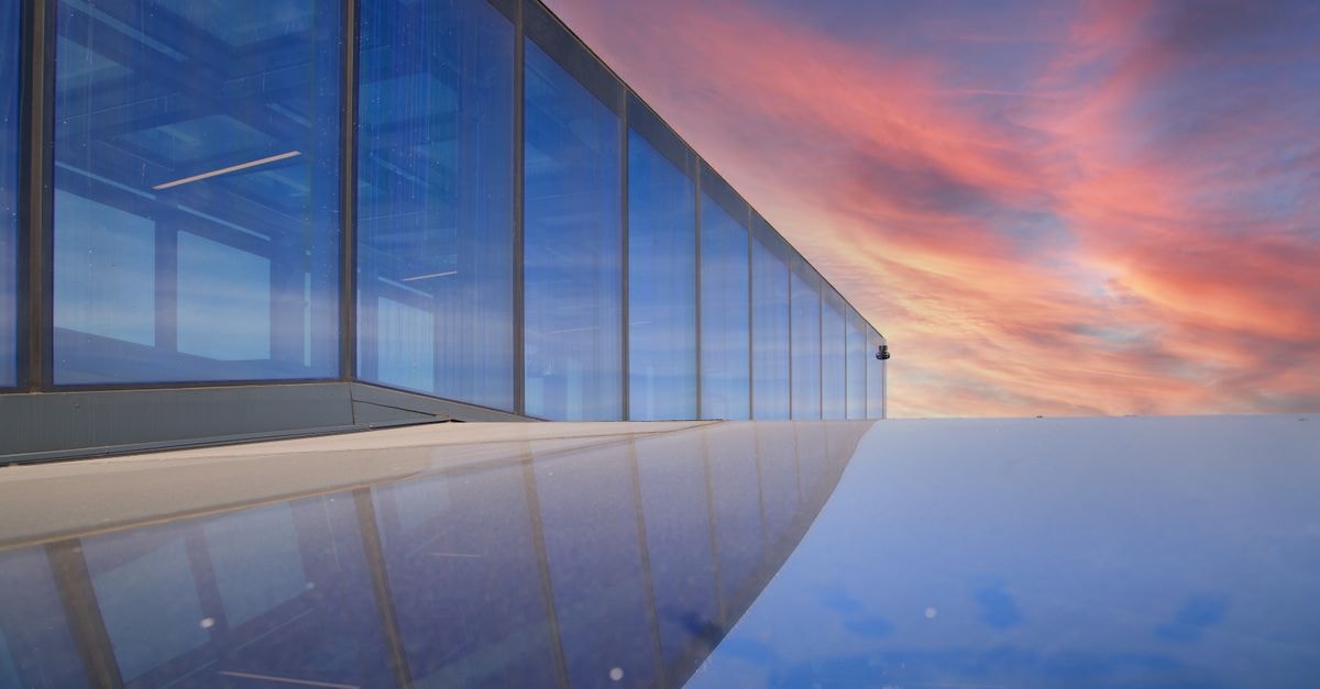 Stunning modern glass facade reflecting vivid sunset sky in Bydgoszcz.