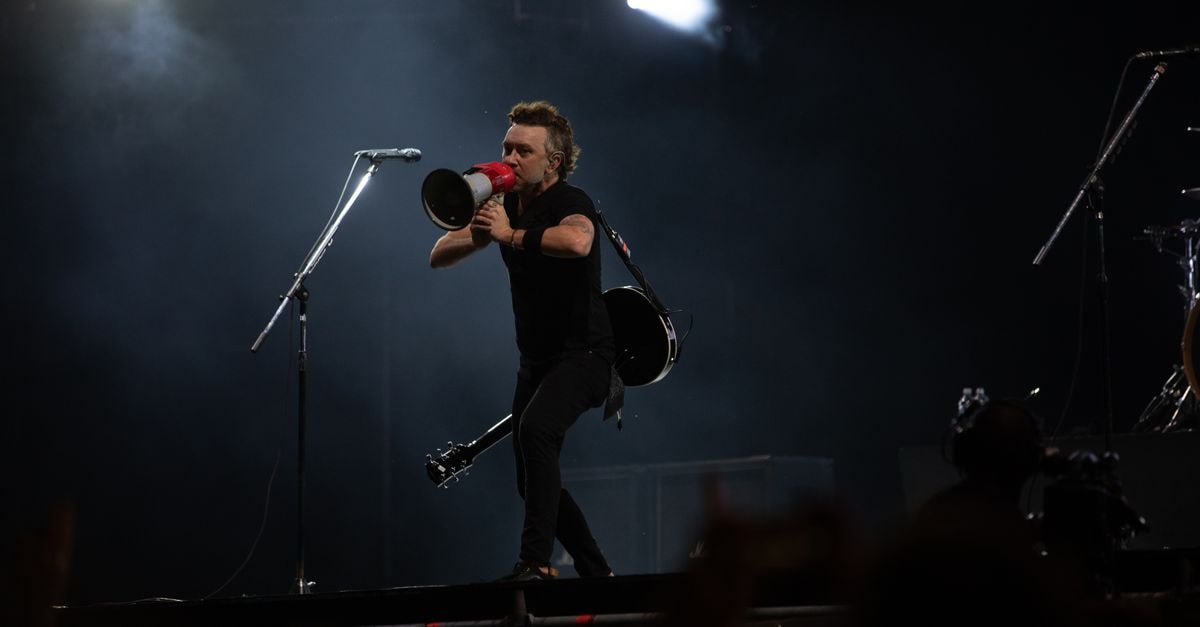 Jonas Brothers announce 45-city North American tour Musician with megaphone on stage during night concert, energizing the crowd.