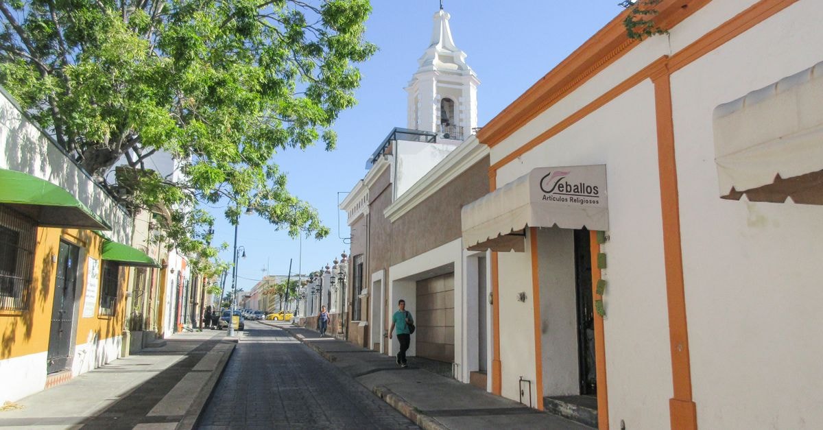 A scenic street view in Manzanillo, Colima featuring traditional architecture and a prominent bell tower.