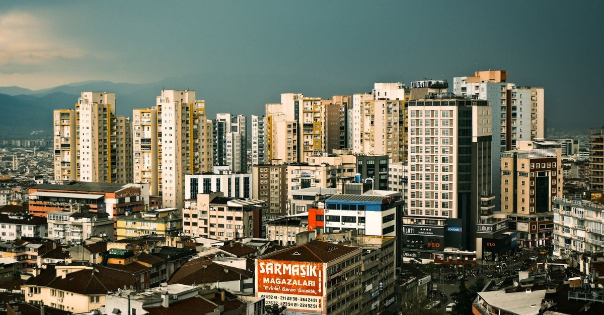 A bustling cityscape of Bursa, Türkiye, showcasing modern high-rise buildings under a cloudy sky.