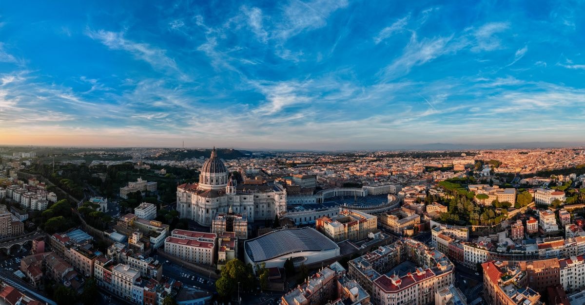 The Spring House Hotel Rome Vatican, Tapestry Collection by Hilton in Vatican City: A Quiet Base Near St. Peter's Panoramic aerial view of St. Peter's Basilica and Vatican City at sunset, showcasing the Rome skyline.