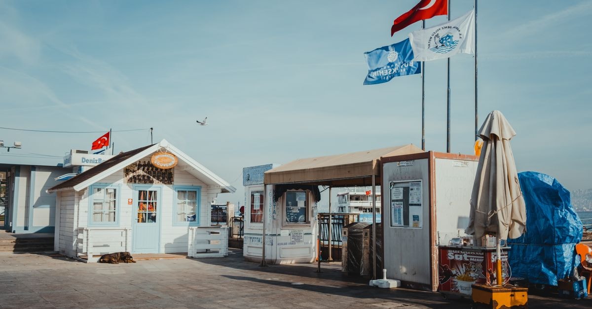 A Quiet Crossroads: An Üsküdar Travel Guide on Istanbul's Asian Shore Charming tourist center by the sea with Turkish flags waving under a clear sky.