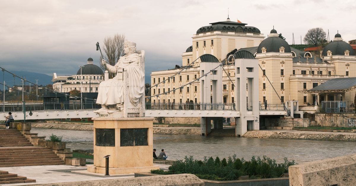 Statue and historic architecture by the river in Skopje, North Macedonia.