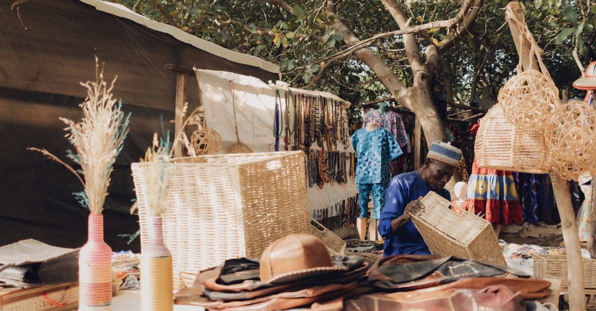 Abomey-Calavi Travel Guide: West African Culture on a Quiet Budget Explore an outdoor Nigerian market showcasing vibrant art and crafts under lush trees.