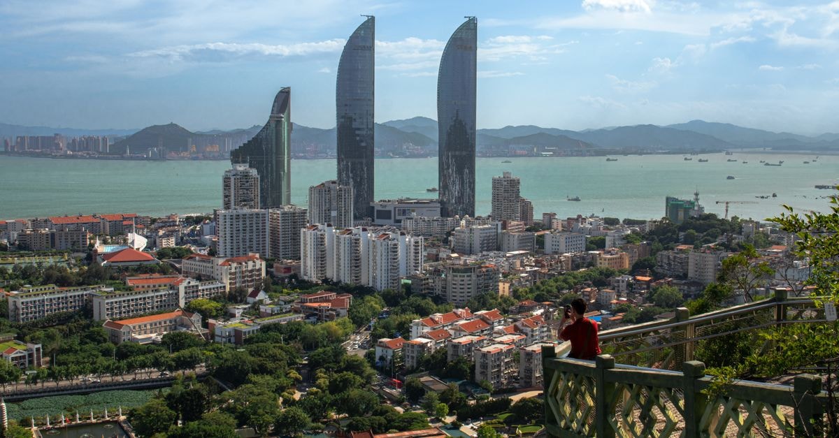 Pan Pacific Xiamen in Xiamen: Lakefront Tower Steps from Metro Line 2 Panoramic view of Xiamen skyline with dramatic sea and skyscrapers on a clear day.