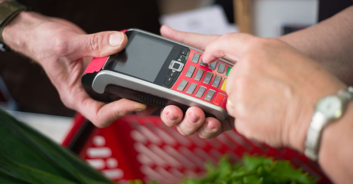 Credit Acceptance Corporation: Patient Capital Meets a Specialized Subprime Lender Two people making a cashless payment at a grocery store with a credit card terminal.