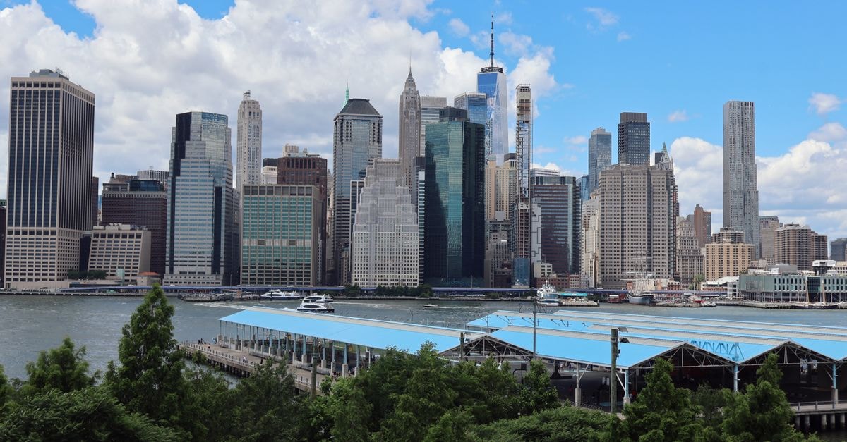 Dramatic view of Downtown Manhattan skyline from Brooklyn with modern skyscrapers and iconic landmarks.