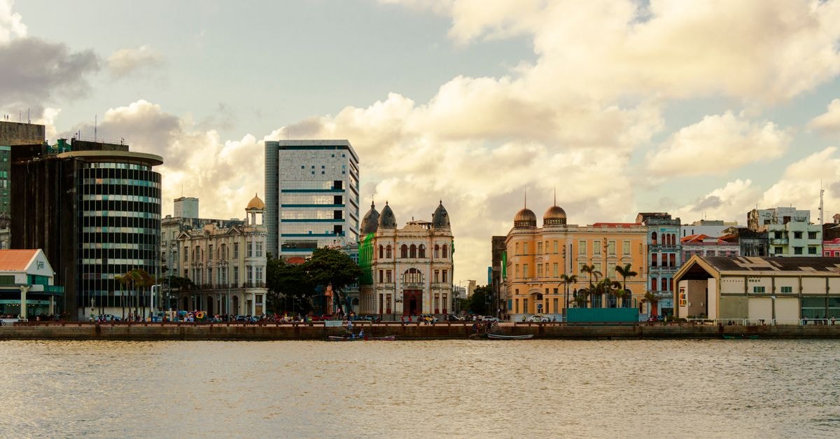 Lido Hotel in Porto Alegre: Historic-Center Stay Near Matriz Plaza Scenic view of Recife's waterfront architecture showcasing historic and modern buildings under a partly cloudy sky.