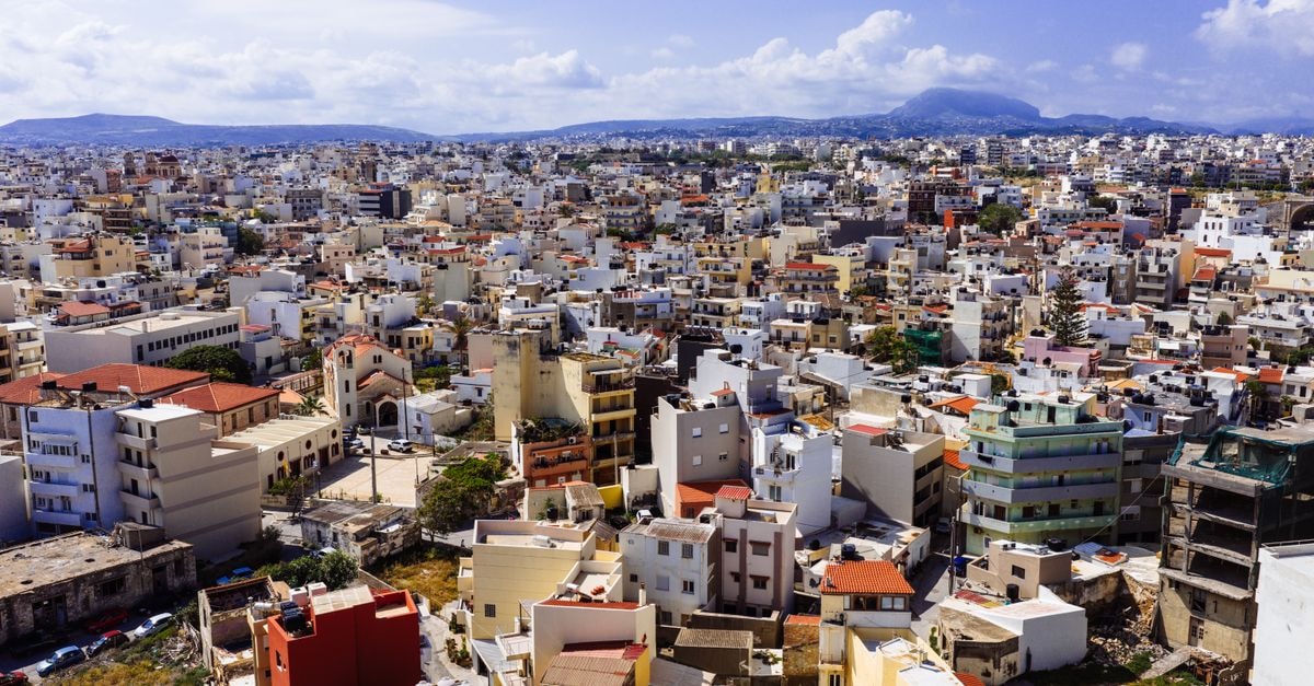 Dimargio Luxury Hotel and Spa, Heraklion — A Heritage Stay in the Old Town Discover the vibrant cityscape of Heraklion, Crete, captured from above with a stunning view of buildings and mountains.