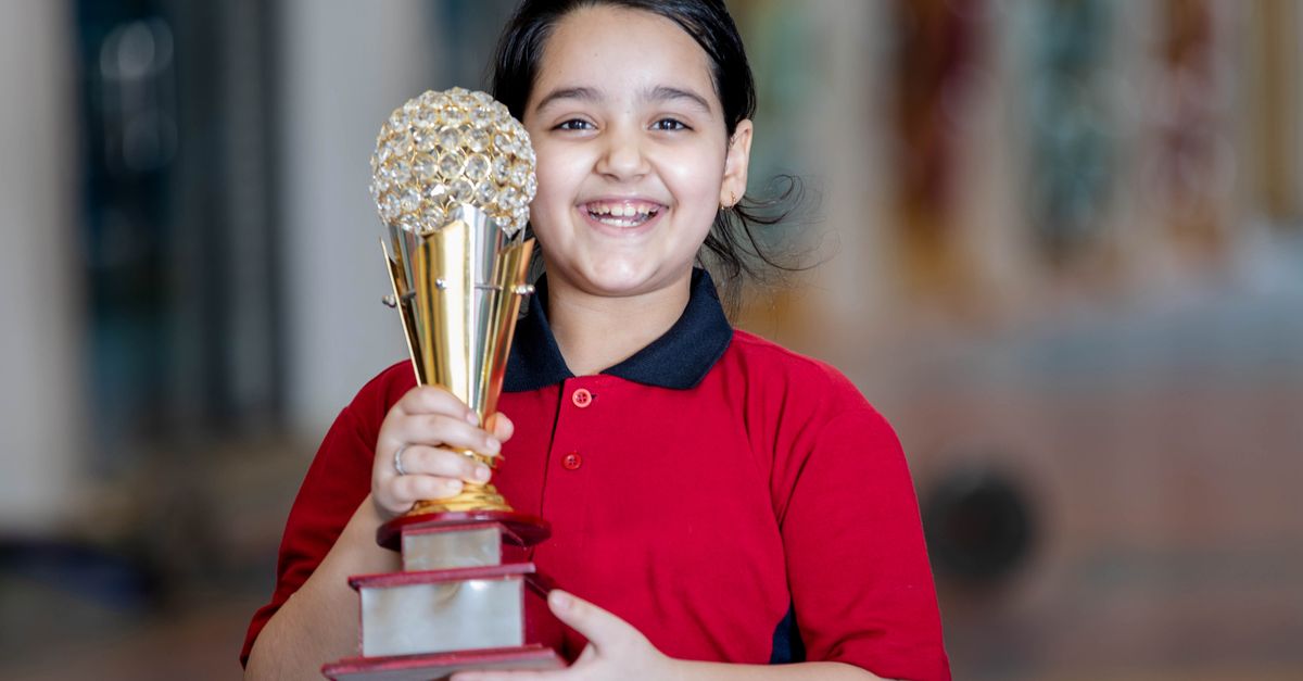 Recent Film Awards Highlight India's National Honors and BAFTA Student Winners Smiling girl proudly holds her trophy indoors, celebrating her achievement.