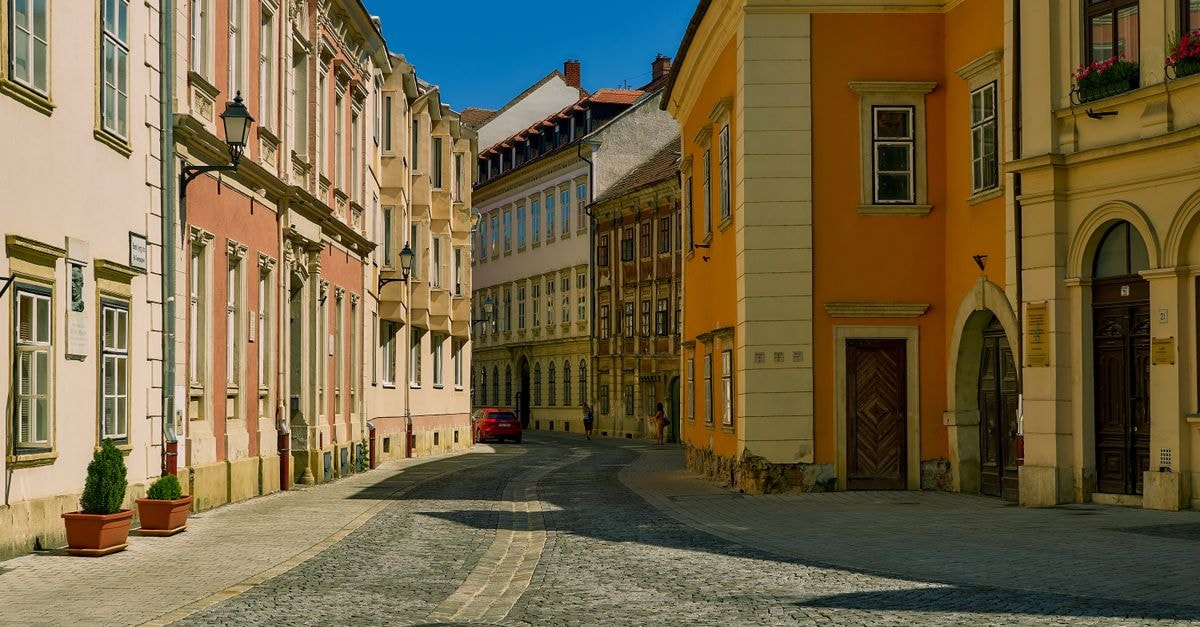Eger Travel Guide: Wine, History and a Slow Day in Hungary A peaceful street in historic Sopron, Hungary featuring colorful buildings under a clear blue sky.