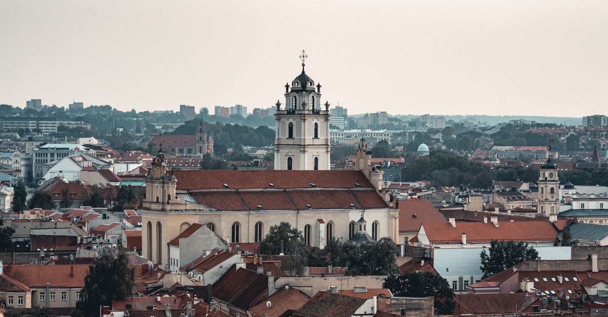 Vilnius Travel Guide: Quiet Corners and Big Flavours A scenic aerial view of Vilnius, Lithuania, featuring a historic church amidst the cityscape.