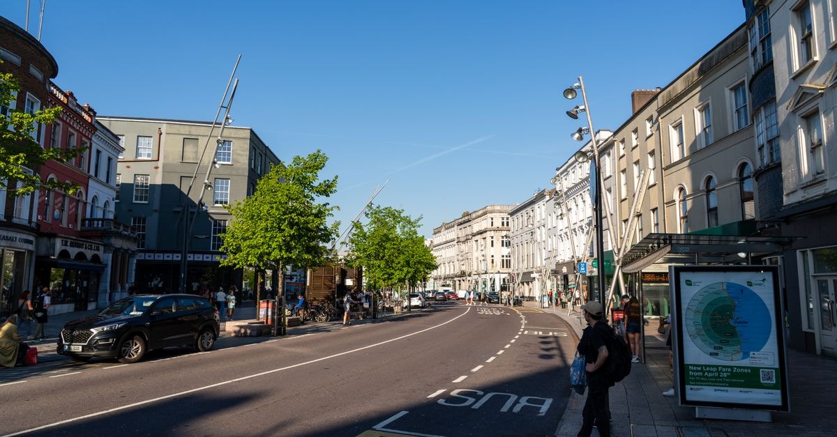 Sunny street view in Cork, Ireland, showcasing vibrant architecture and daily urban life.