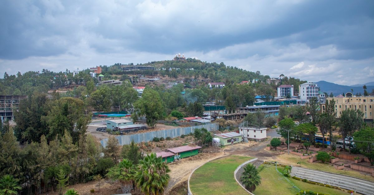 Captivating aerial view of Gondar, Ethiopia with lush greenery and architecture under a cloudy sky.