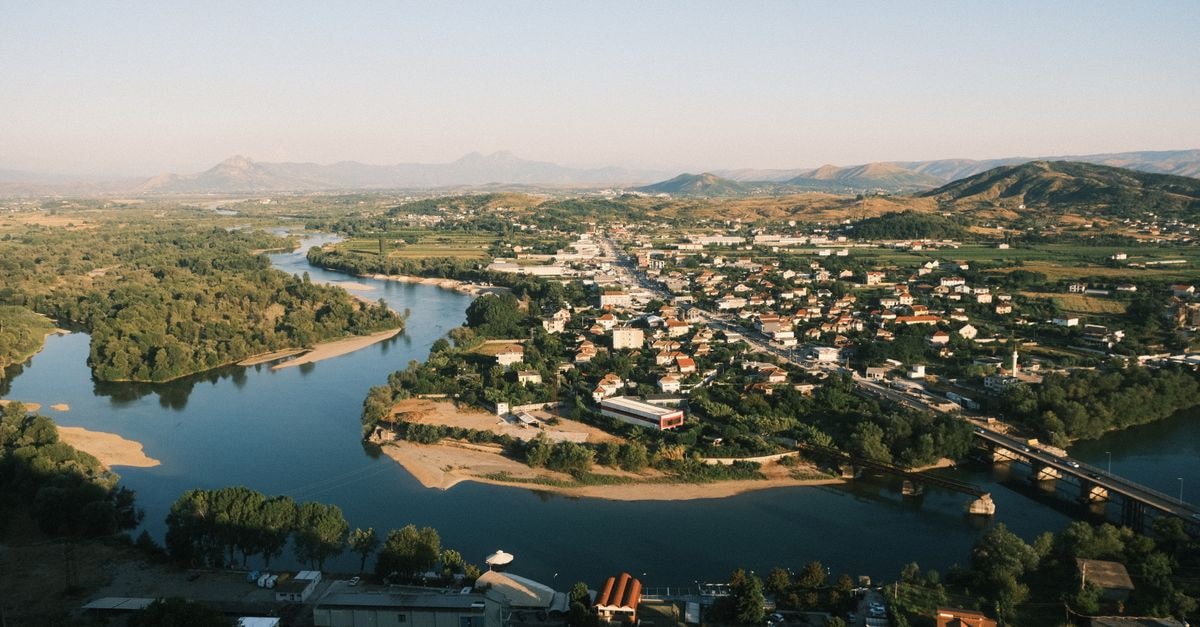 Shkoder Travel Guide: Planning Tips, Costs and Things to Do Beautiful aerial view of Shkodër city with meandering river and surrounding mountains.