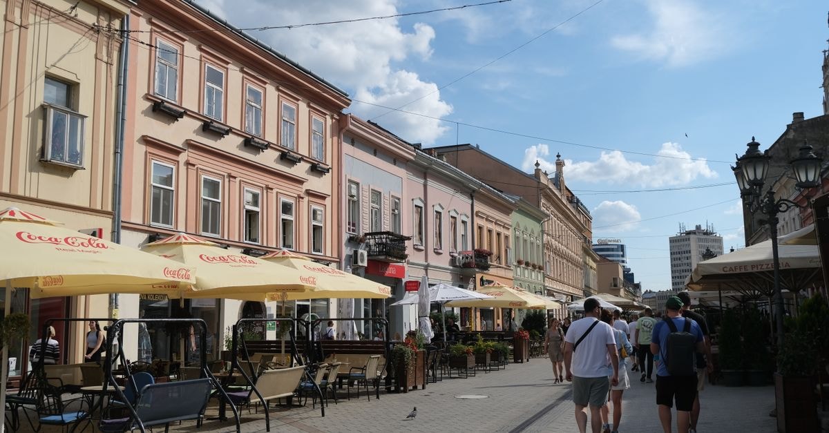 Garni Hotel Planeta Inn in Novi Sad: A Compact City Stay Street view of Novi Sad, Serbia with people enjoying outdoor cafes.