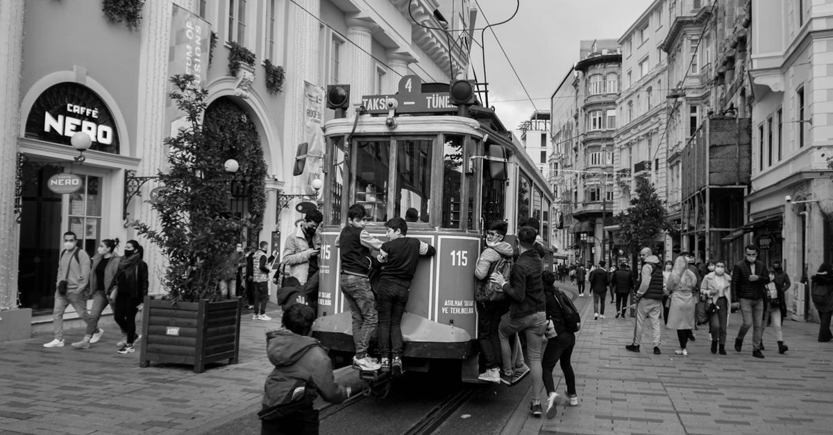Kurgan travel guide: riding trams and finding comfort food Grayscale image of people riding a vintage tram on a busy street in Istanbul, Turkey.