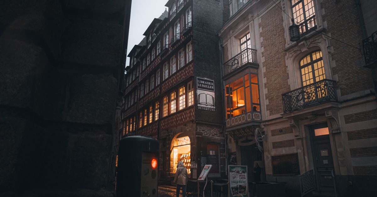 Nighttime view of stunning historic architecture and illuminated bookstore entrance in Rennes, France.