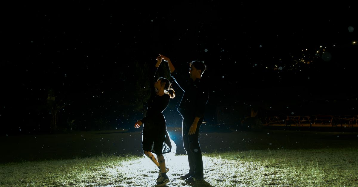 "Dancing with the Stars: The Next Pro" Cuts Field to Eight After Medical Elimination A couple dances under the night sky, illuminated by gentle light, creating a romantic mood.