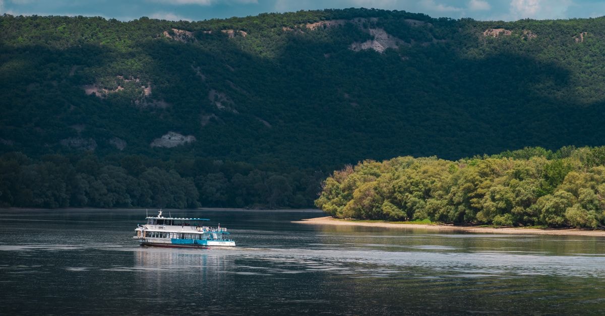 Gatineau Travel Guide: Riverside Escapes and Refined Flavors A scenic view of a boat cruising on the Danube River with lush hills and forested banks in Hungary.
