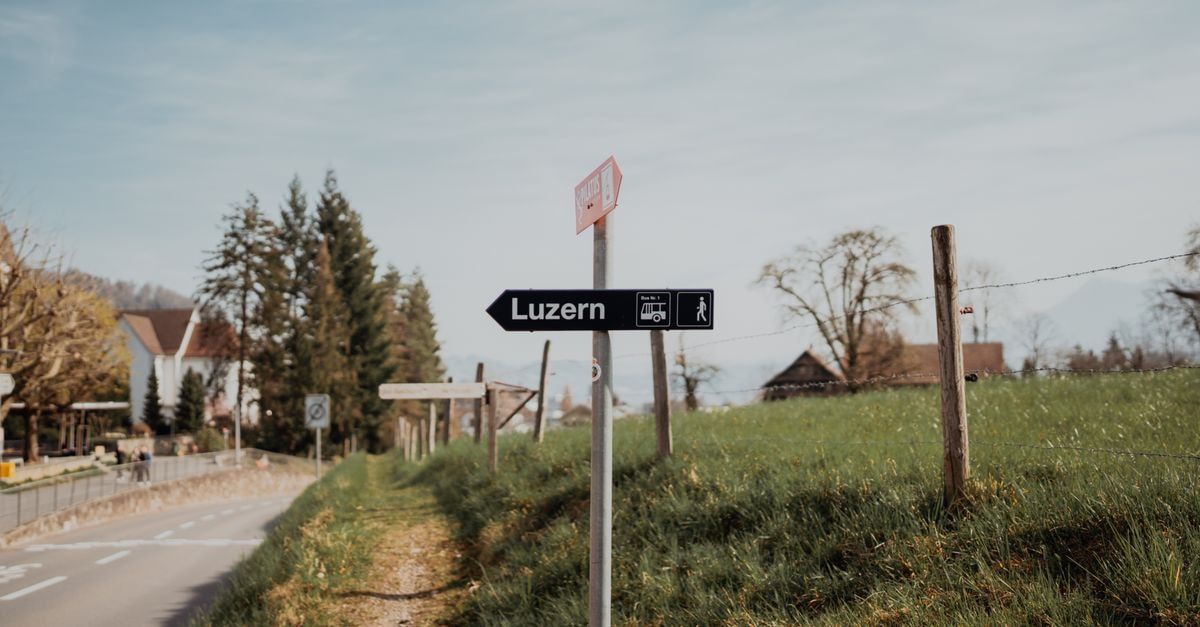 A scenic road sign pointing to Lucerne on a tranquil rural road in Switzerland.