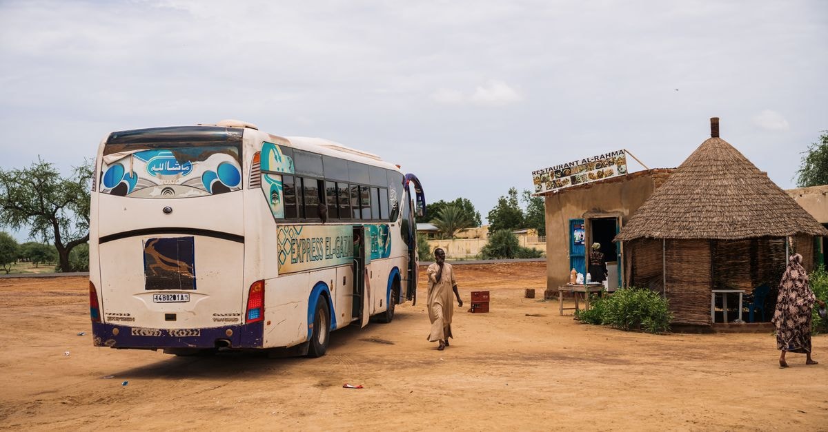 Sarh Travel Guide: Slowing Down in Chad's Southern Cotton Capital A white bus stops at a rural village with a tribal hut and local restaurant.