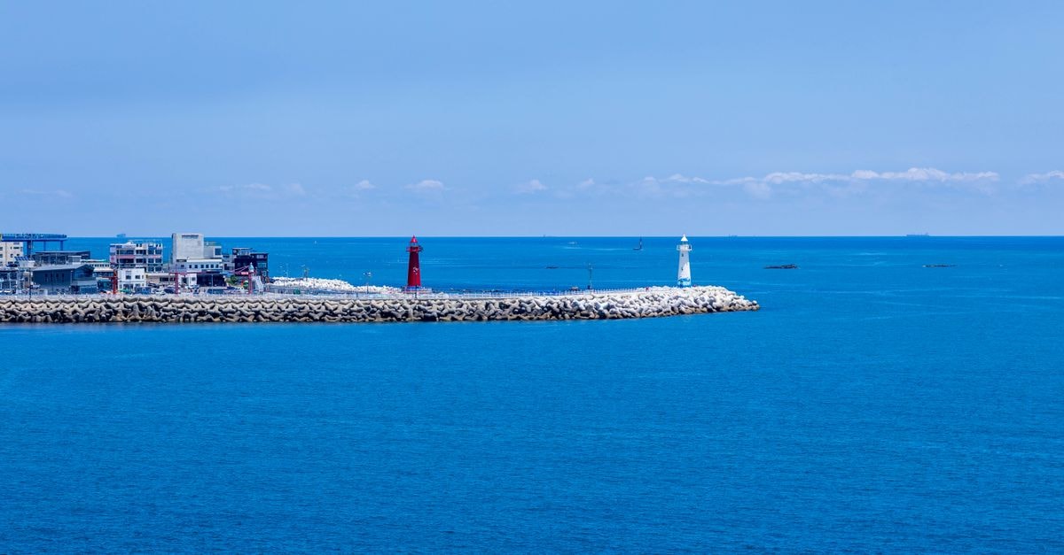 Tranquil scene of two lighthouses by the sea in Busan, South Korea, under a clear blue sky.