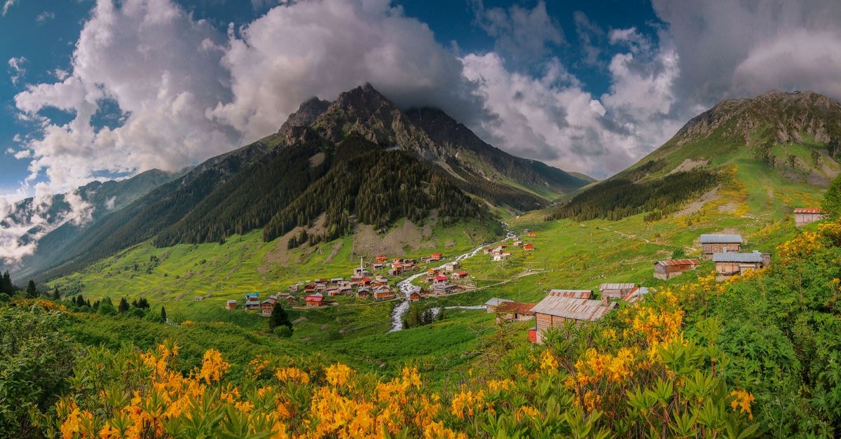 Karabaglar Travel Guide: Planning Tips, Costs and Things to Do Stunning mountain village with vibrant flowers, lush green hills, and dramatic clouds in a picturesque valley in summer.