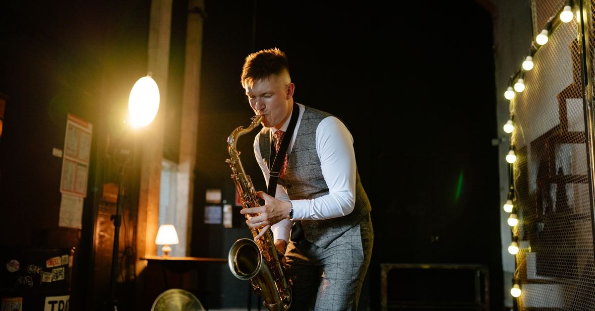 Jazz Hostel Pskov: Steps from the Kremlin Walls Musician plays saxophone in dimly lit room, creating moody jazz ambiance.