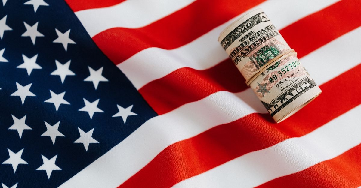 From above of United States currency folded in roll placed on USA flag illustrating concept of business profit and wealth