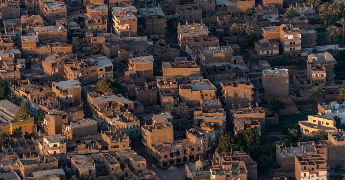 Par 4 Chemins - Atypical Stopover in Nouakchott: A Cozy Mauritanian Lodge Discover the unique architecture of a desert town with traditional clay buildings from an aerial perspective.