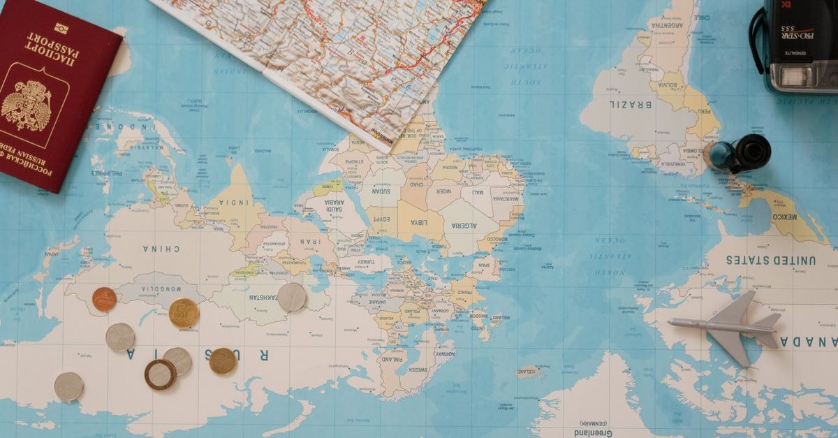 Saskatoon Travel Guide for August 2026: Planning Tips and Costs Flat lay of a world map, passport, coins, and camera for travel planning.