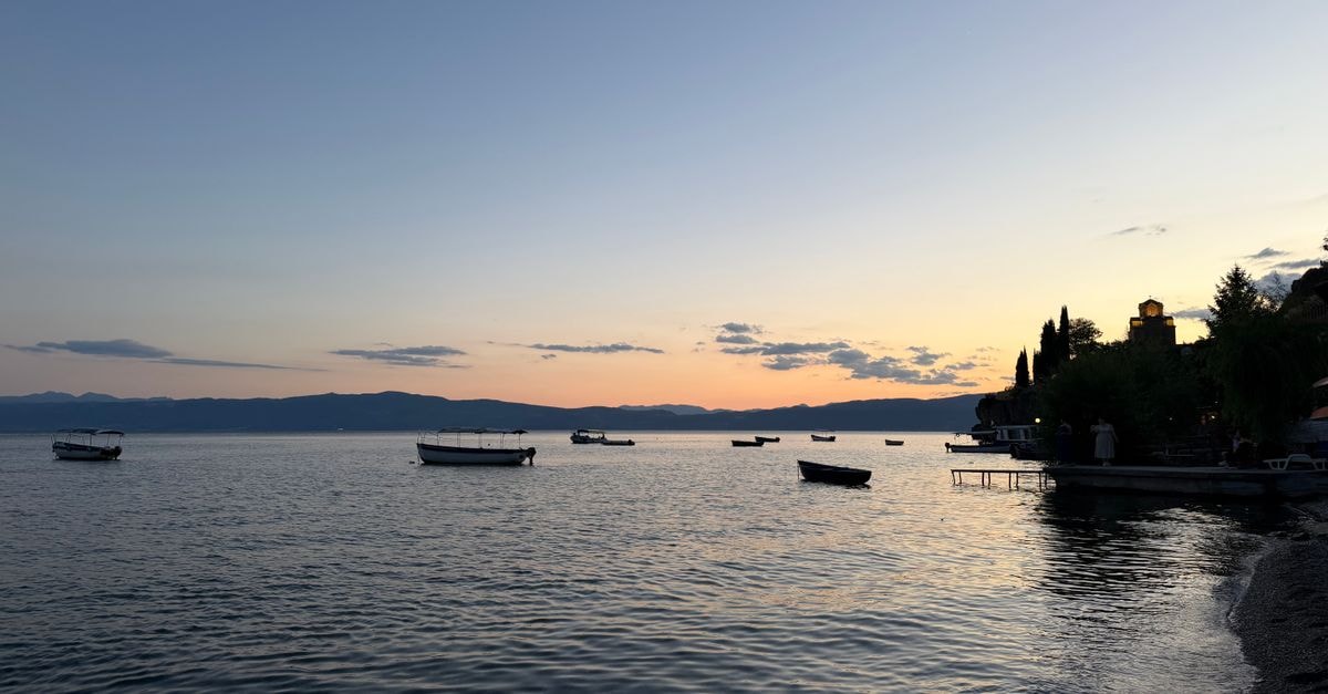A tranquil sunset view over Lake Ohrid with boats floating peacefully near the shore.