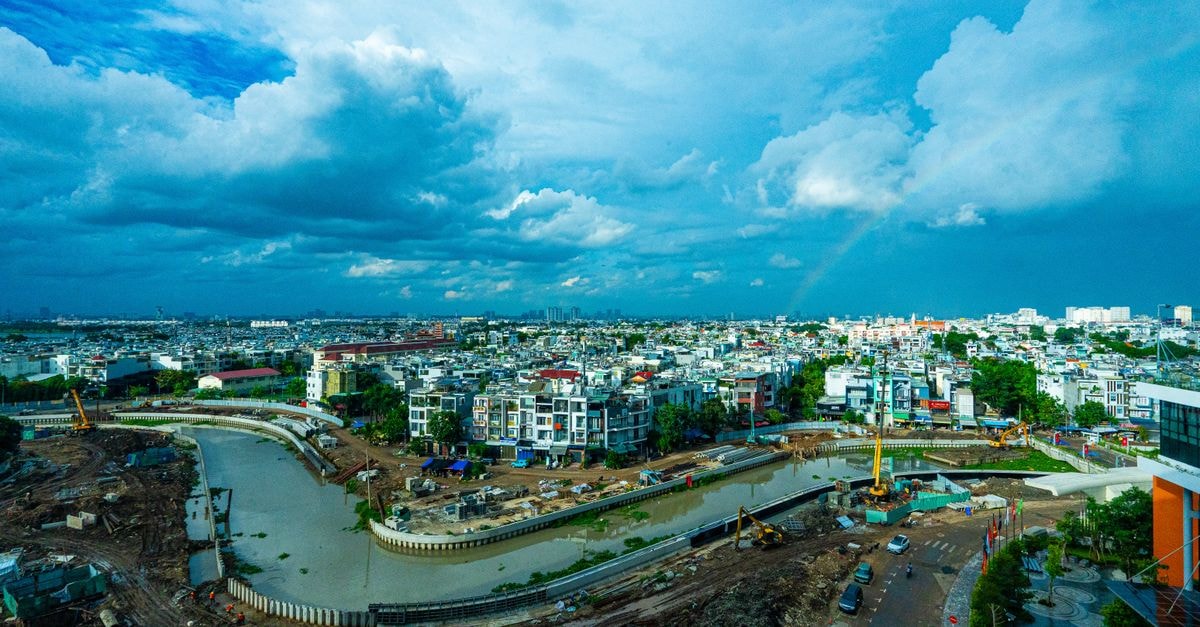 Ninh Kiều Riverside Hotel, Can Tho: A Riverside Spot with Two Frontages Cityscape featuring ongoing construction around a river with a vivid rainbow in a cloudy sky.