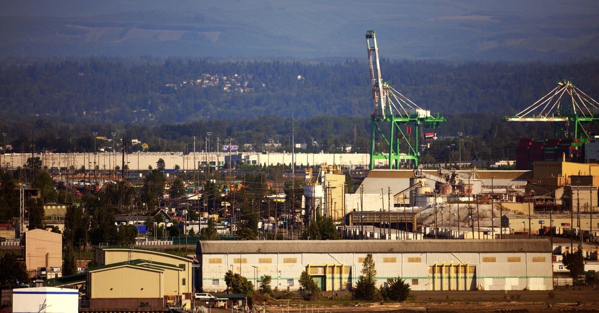 A scenic view of an industrial port with cranes and warehouses at daytime.