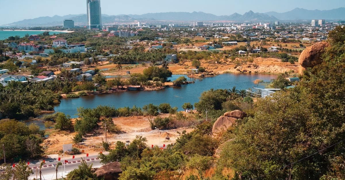 Nhà khách 71 in Biên Hòa: A Quiet Đồng Nai Address on Hà Huy Giáp Aerial view of a vibrant cityscape with a lake and mountains, captured during a sunny summer day.