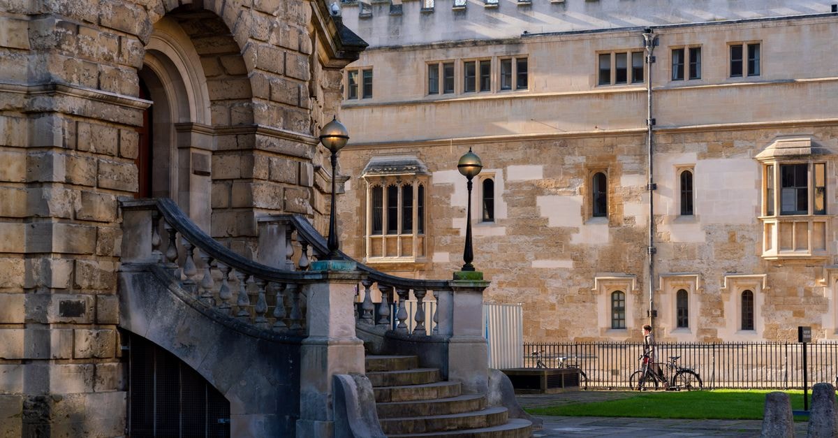 Oxford Travel Guide: Planning Tips, Costs and Things to Do Elegant stone staircase and historic university building in Oxford, England on a sunny day.